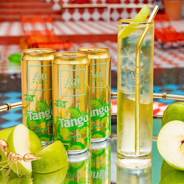 Au Vodka Tango Apple cans and a glass with a gold straw and apple slice