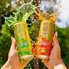 Hands holding two Au Vodka Tango cans, apple and orange, with liquid splashing from the tops