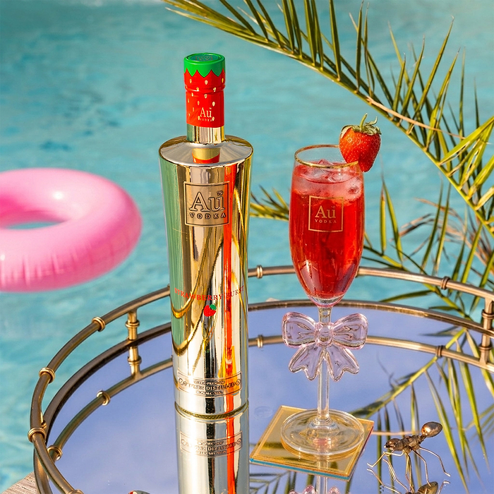 Au Vodka Strawberry Burst bottle and cocktail on a mirrored tray by a pool