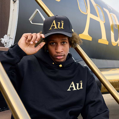 Person wearing a black hoodie and cap with 'Au' logo in front of a branded jet