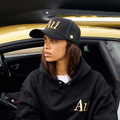 Person wearing a black cap with 'Au' logo sitting inside a car.