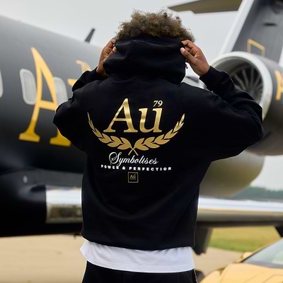 Person wearing a black hoodie with gold 'Au' logo on the back.