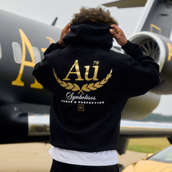 Person wearing a black hoodie with gold 'Au' logo on the back.
