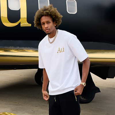 Man wearing a white t-shirt with gold "AU" lettering outside