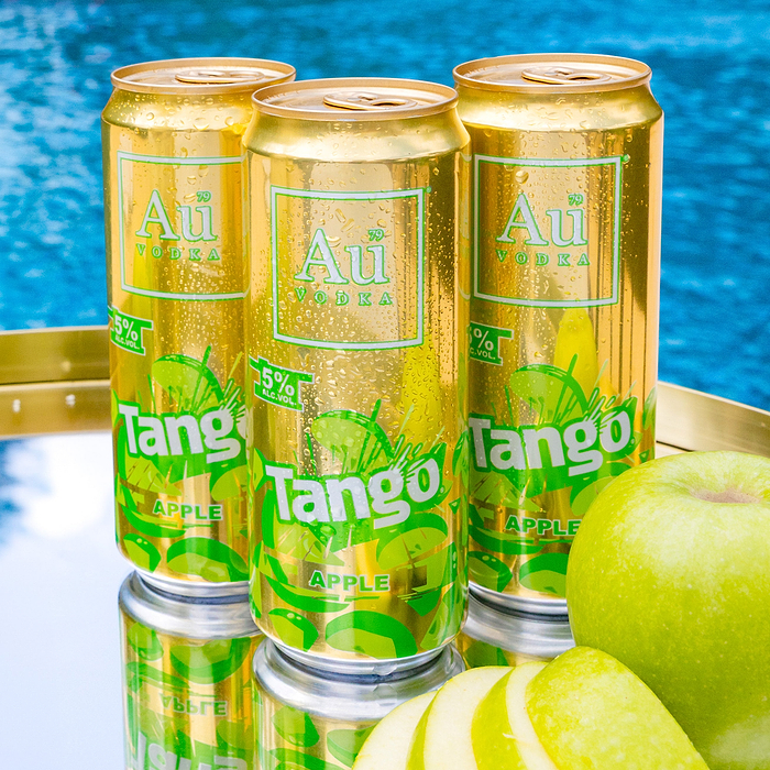 Three Au Vodka Tango Apple cans with water droplets, next to a whole and sliced green apple