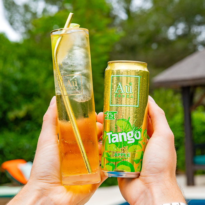 Hands holding a glass of Au Vodka and a can of Au Vodka Tango Apple