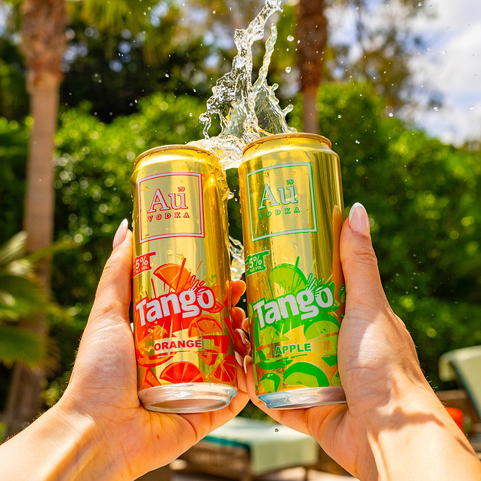 Two Au Vodka Tango cans, orange and apple flavors, held up with water splashing