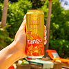 Hand holding a cold Au Vodka Tango Orange can with water droplets, against a blurred green background