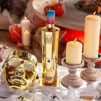 Au Vodka Bubblegum bottle with a gold mask and candles on a table with spider webs