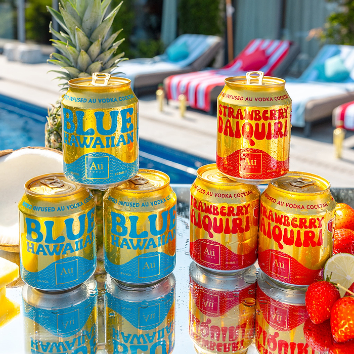 Au Vodka Blue Hawaiian and Strawberry Daiquiri cans by a pool with pineapple, coconut, and strawberries