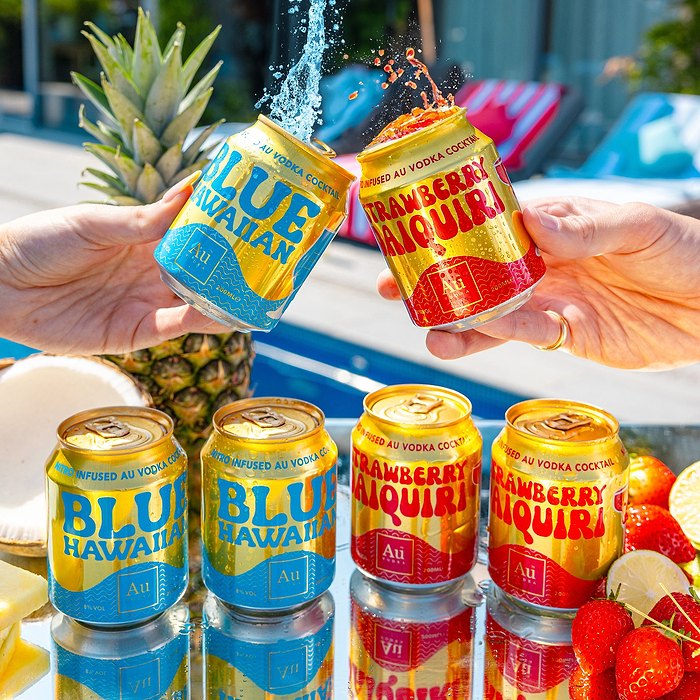 Hands holding two Au Vodka cocktail cans, Blue Hawaiian and Strawberry Daiquiri, with liquid splashing out