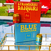Au Vodka Strawberry Daiquiri and Blue Hawaiian 12-pack boxes and cans on a gold mirrored tray