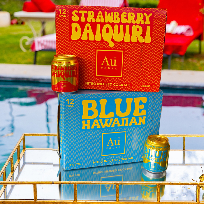 Au Vodka Strawberry Daiquiri and Blue Hawaiian 12-pack boxes and cans on a gold mirrored tray