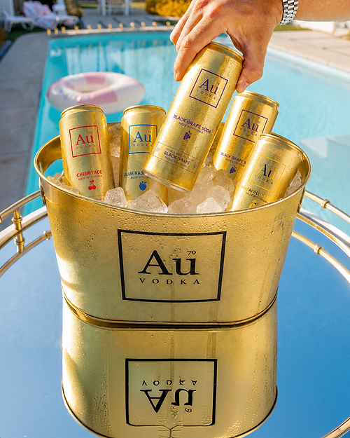 Au Vodka cans in a gold ice bucket by a swimming pool