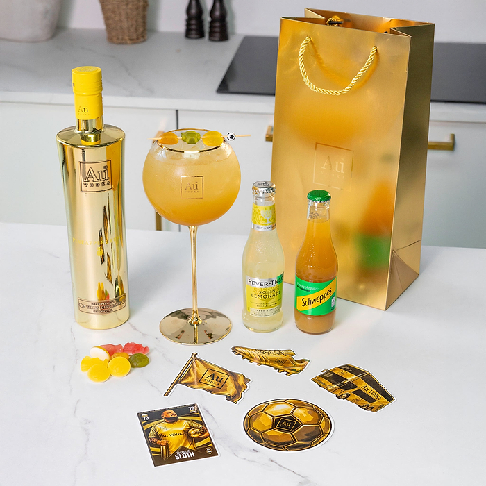 Au Vodka Pineapple Crush bottle with cocktail glass mixers and branded stickers on a kitchen counter