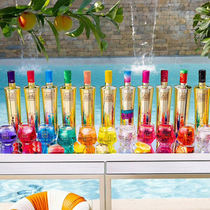 Au Vodka bottles and cocktails by a pool with a waterfall and peaches hanging from a tree