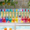 Au Vodka bottles and cocktails in various colors on a reflective surface by a pool