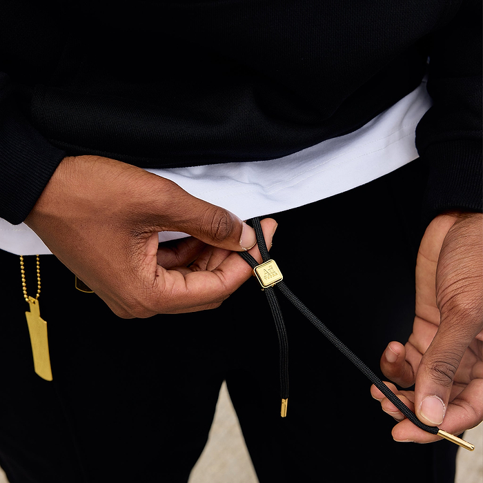 Person adjusting a black lanyard with a gold clasp