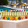 Au Vodka bottles and cocktails in various colors by a pool