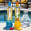 Au Vodka bottles and glasses by a pool. Blue Raspberry and Miami Mango vodka bottles, blue and yellow drinks