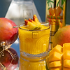 Au Vodka mango cocktail with mango slices and chili powder, whole mangoes, and Au Vodka bottles