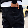 Person wearing black joggers with black 'AU' logo on back pocket