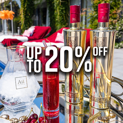 Two gold Au Vodka bottles, a glass of ice, and a red cocktail with cherries on a silver tray