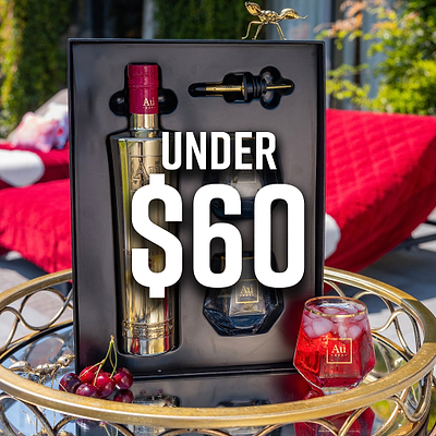 Au Vodka gift set with a gold bottle, a black bottle, a pourer, and a red drink in a glass