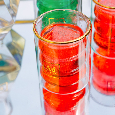 Au Vodka branded double walled glassware containing red liquid and ice