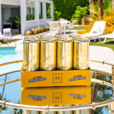 Six-pack of Au Vodka USA Pineapple Crush cans on a tray by a pool