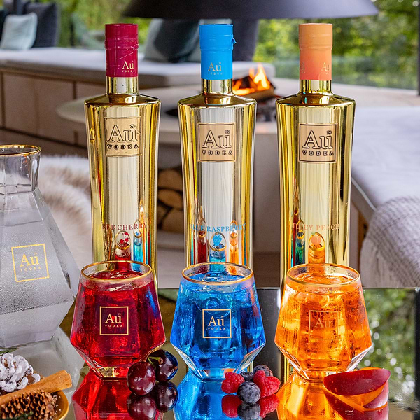 Au Vodka Red Cherry Blue Raspberry and Juicy Peach bottles with matching cocktails and fresh fruit