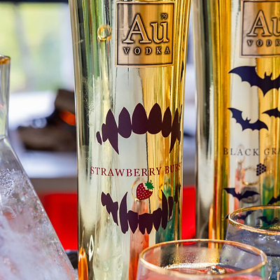 Two bottles of Au Vodka with Halloween-themed labels on a blurred background