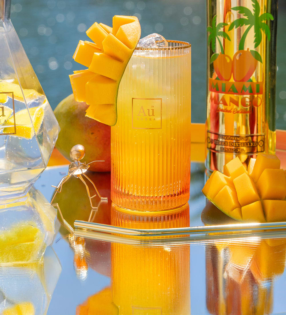 Au Vodka Miami Mango cocktail with mango slices and a bottle of Au Vodka Miami Mango