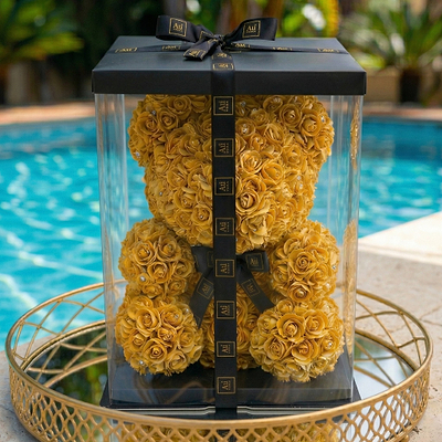 Au Vodka USA merchandise: Gold rose teddy bear in clear box with black ribbon, on a gold tray by a pool