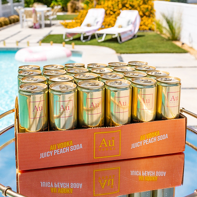 Au Vodka Juicy Peach Soda Cocktail Cans in a case by a pool
