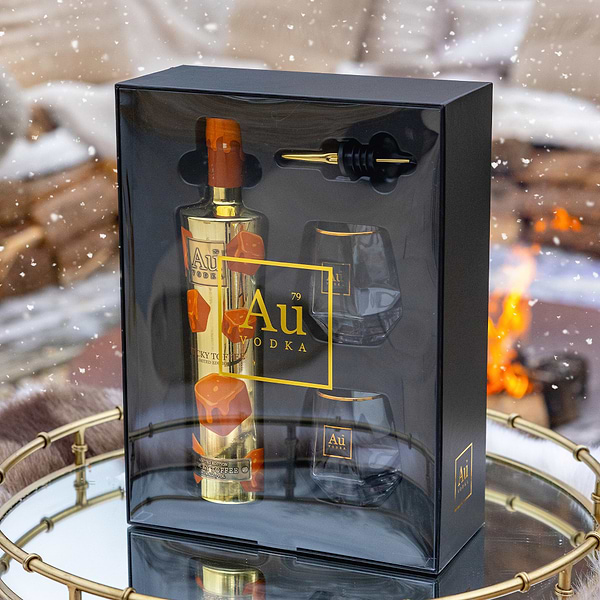 Au Vodka gift set with bottle, glasses, and bar tools in a decorative box against a snowy background.