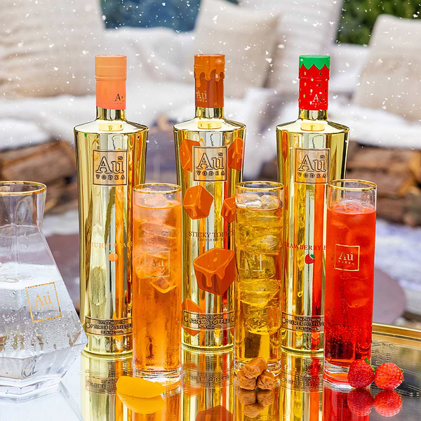 Au Vodka Juicy Peach Sticky Toffee and Strawberry Burst bottles with matching cocktails and fresh fruit