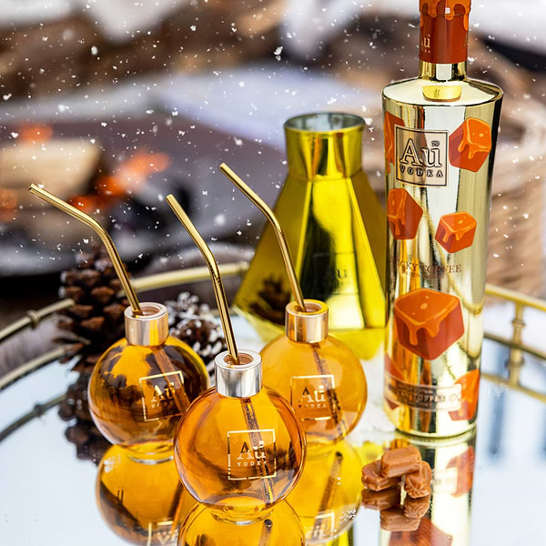 Decorative bottles with gold and orange design on a reflective surface with blurred background