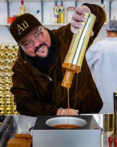 Man wearing Au branded cap pouring liquid from gold bottle into metal container