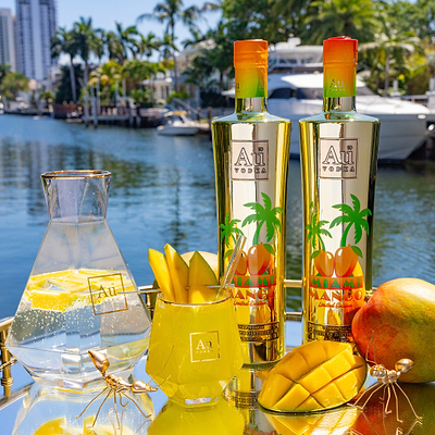 Au Vodka USA Mango Passion bottle and drinks on a tray with mangoes by a canal