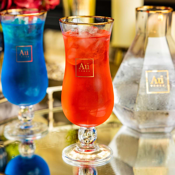 Au Vodka branded glassware featuring red and blue cocktails on a mirrored surface