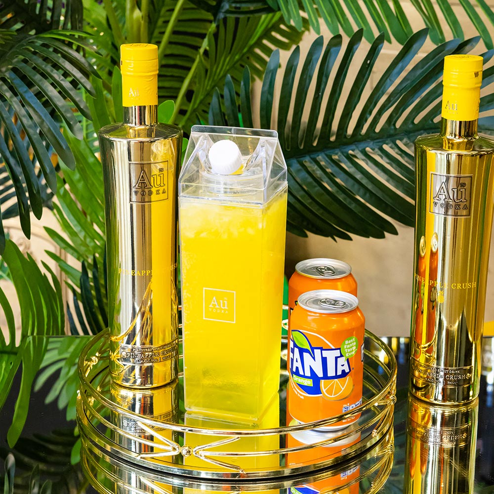 Au Vodka bottles next to a clear carton of yellow cocktail and a can of Fanta