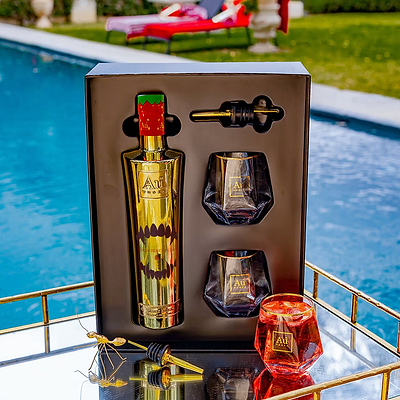 Au Vodka Strawberry Burst gift pack with gold bottle, two glasses, and pourer by a pool