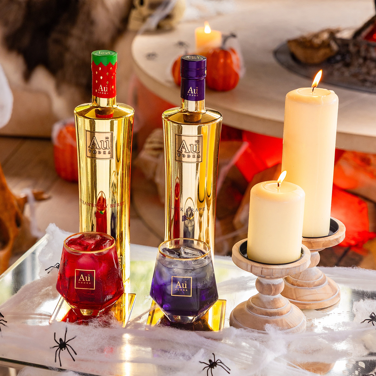 Au Vodka Strawberry Burst and Black Grape bottle bundle with matching cocktails and candles on a table