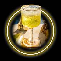 Au Vodka glass with yellow liquid and pineapple in background