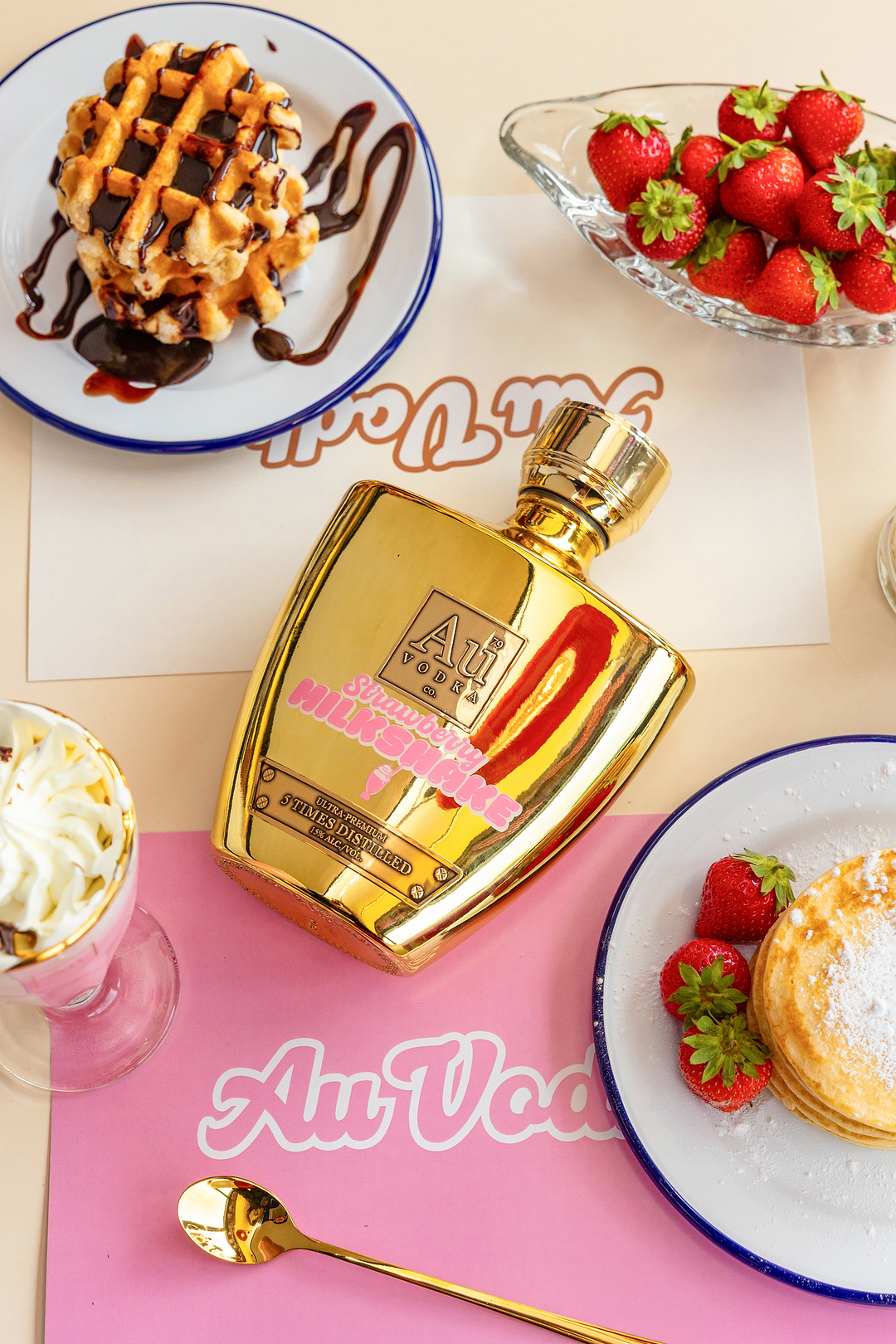 Au Vodka Strawberry Milkshake bottle surrounded by waffles pancakes strawberries and a milkshake