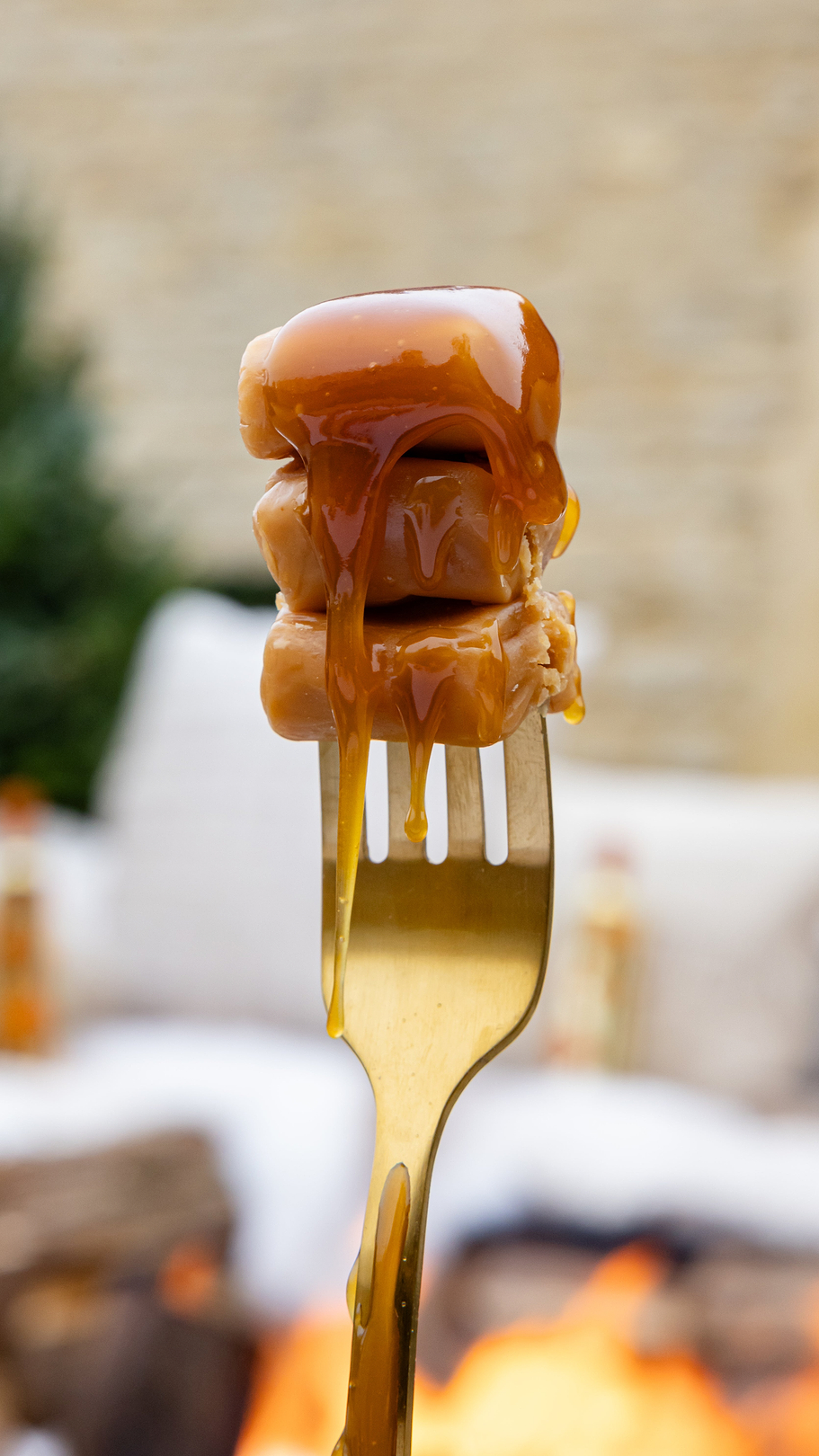 Three caramel cubes on a gold fork with caramel sauce dripping down