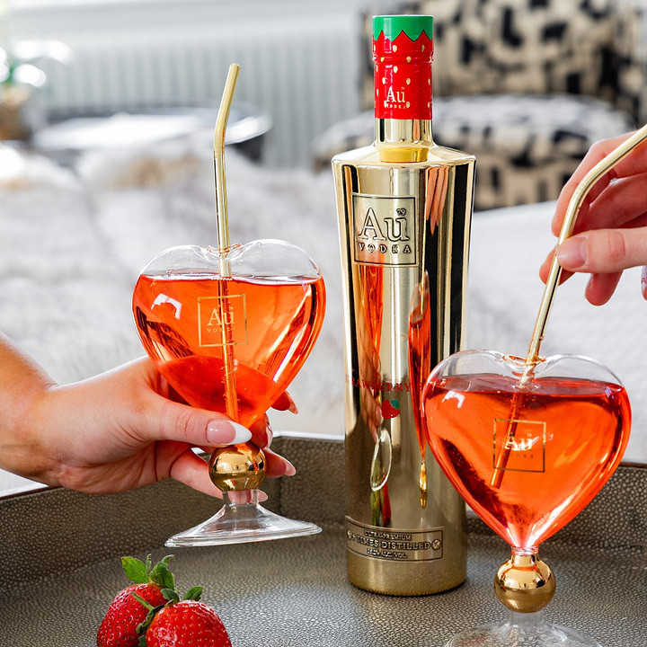 Au Vodka Strawberry bottle with two heart shaped glasses filled with red cocktail on a tray