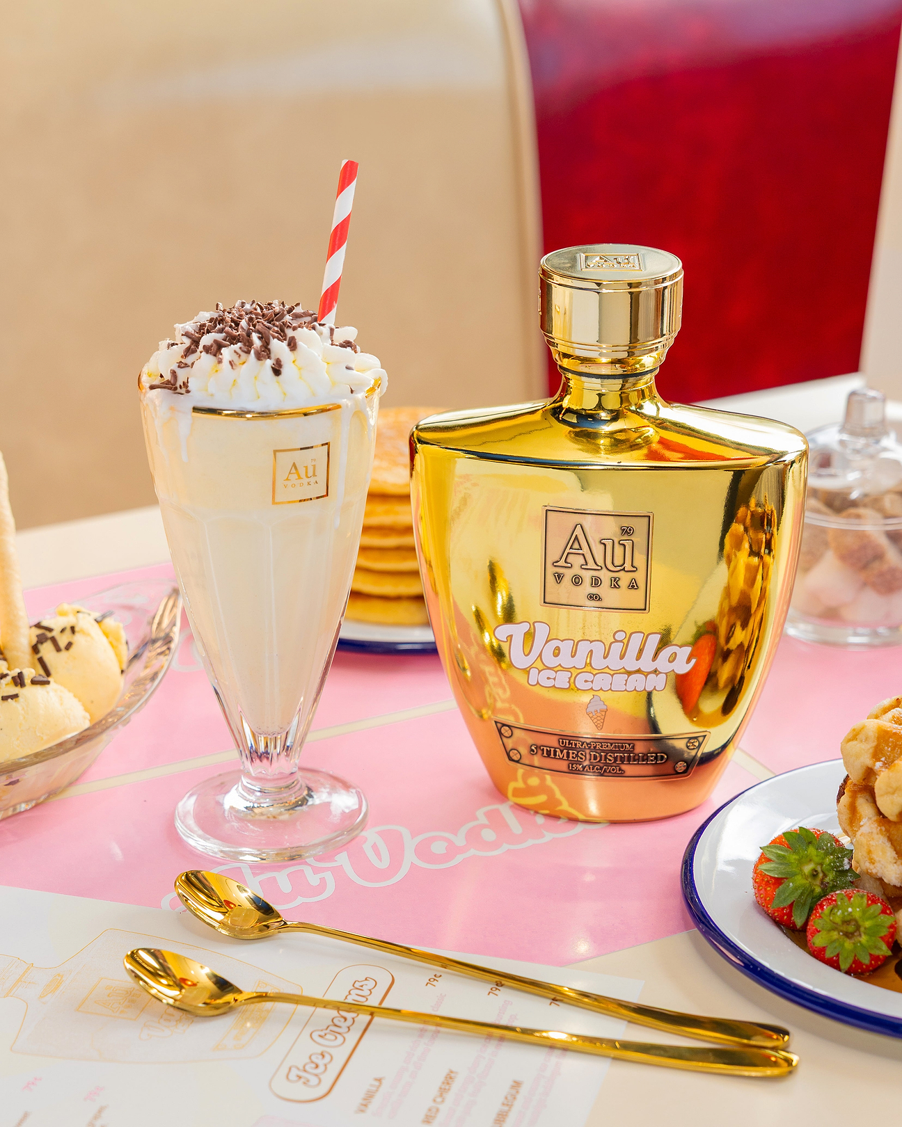 Au Vodka Vanilla Ice Cream bottle next to a milkshake with whipped cream and a striped straw on a table