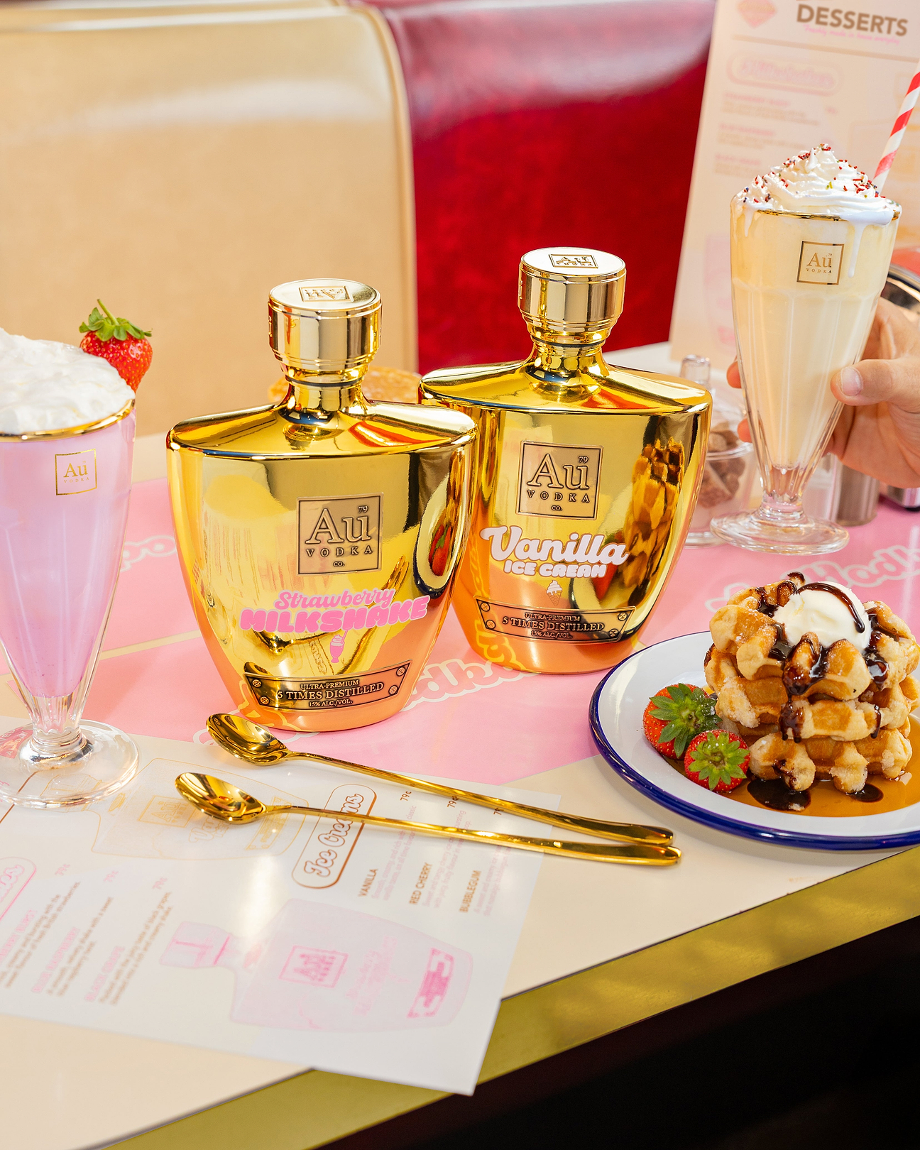 Au Vodka Strawberry Milkshake and Vanilla Ice Cream bottles on a diner table with milkshakes and waffles